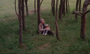 Movie still from “The Sacrifice” (1986), directed by Andrei Tarkovsky – An old man and a young boy sitting in the grass; Wide shot, High angle