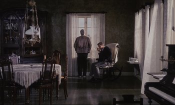 Movie still from “The Sacrifice” (1986), directed by Andrei Tarkovsky – Two men are standing in a room with a window open; Wide shot, High angle