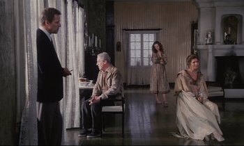 Movie still from “The Sacrifice” (1986), directed by Andrei Tarkovsky – A group of people sitting in a living room next to each other; Wide shot, High angle