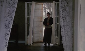 Movie still from “The Sacrifice” (1986), directed by Andrei Tarkovsky – A woman standing in front of open doors; Wide shot, Low angle