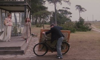 Movie still from “The Sacrifice” (1986), directed by Andrei Tarkovsky – A man on a bicycle carrying a wooden box; Wide shot, Low angle