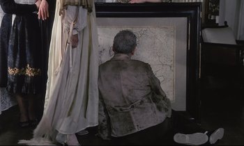 Movie still from “The Sacrifice” (1986), directed by Andrei Tarkovsky – A man sitting in front of a map of the world; Medium shot, High angle