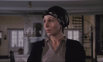 Movie still from “The Sacrifice” (1986), directed by Andrei Tarkovsky – A woman wearing a head scarf in a living room; Close Up shot, Low angle