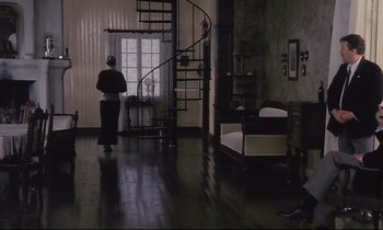 Movie still from “The Sacrifice” (1986), directed by Andrei Tarkovsky – A woman standing in front of a spiral stair case; Wide shot, High angle