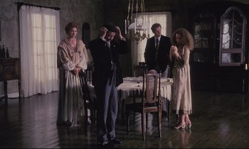 Movie still from “The Sacrifice” (1986), directed by Andrei Tarkovsky – A group of people standing around a dining room table; Wide shot, High angle
