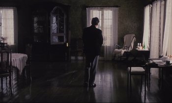 Movie still from “The Sacrifice” (1986), directed by Andrei Tarkovsky – A man standing in front of a window in a living room; Wide shot, Low angle