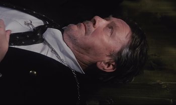 Movie still from “The Sacrifice” (1986), directed by Andrei Tarkovsky – A person laying on the ground wearing a suit; Close Up shot, High angle