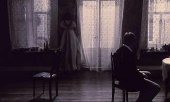 Movie still from “The Sacrifice” (1986), directed by Andrei Tarkovsky – A man and a woman sitting in front of a window; Wide shot, High angle
