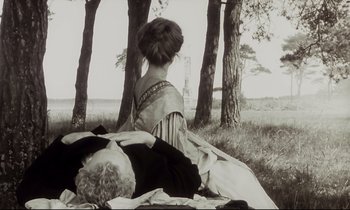 Movie still from “The Sacrifice” (1986), directed by Andrei Tarkovsky – A woman sitting on the ground near some trees; Medium shot, Over the shoulder angle