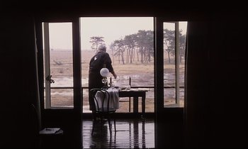 Movie still from “The Sacrifice” (1986), directed by Andrei Tarkovsky – A man standing in front of an open window; Wide shot, Over the shoulder angle