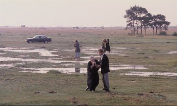 Movie still from “The Sacrifice” (1986), directed by Andrei Tarkovsky – A man and a woman standing in the grass; Extreme Wide shot, High angle