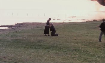 Movie still from “The Sacrifice” (1986), directed by Andrei Tarkovsky – A man kneeling down next to a woman on a field; Extreme Wide shot, High angle