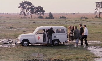 Movie still from “The Sacrifice” (1986), directed by Andrei Tarkovsky – A group of people standing next to an ambulance; Wide shot, High angle