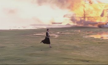 Movie still from “The Sacrifice” (1986), directed by Andrei Tarkovsky – A woman running through a field with a fire in the background; Extreme Wide shot, High angle