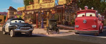 Movie still from “Cars 2” (2011), directed by John Lasseter – An old car parked on the side of the street; Wide shot, High angle