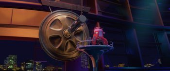 Movie still from “Cars 2” (2011), directed by John Lasseter – A red car is sitting in front of a gold wheel; Extreme Wide shot, Low angle