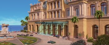 Movie still from “Cars 2” (2011), directed by John Lasseter – A large building with cars parked in front of it; Extreme Wide shot, Low angle