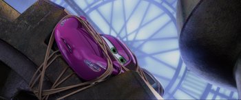 Movie still from “Cars 2” (2011), directed by John Lasseter – A purple toy car tied up to a pole; Wide shot, Low angle