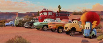 Movie still from “Cars 2” (2011), directed by John Lasseter – A group of cars are lined up in front of a fire truck; Wide shot, Low angle