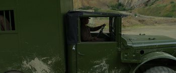 Movie still from “Carter” (2022), directed by Jung Byung-gil – A man sitting inside of an old train car; Wide shot, High angle