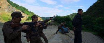 Movie still from “Carter” (2022), directed by Jung Byung-gil – A group of men in brown uniforms are playing a game; Wide shot, Over the shoulder angle