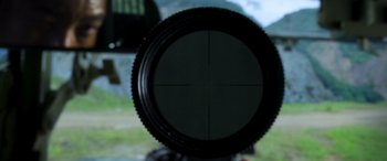 Movie still from “Carter” (2022), directed by Jung Byung-gil – A rifle scope in a field with mountains in the background; Extreme Close Up shot, Overhead angle