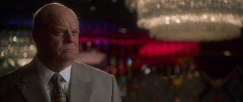 Movie still from “Casino” (1995), directed by Martin Scorsese – An older man wearing a suit and tie in front of lights; Close Up shot, Over the shoulder angle