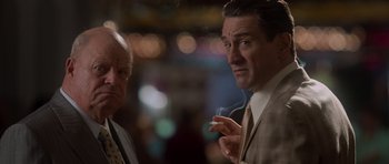 Movie still from “Casino” (1995), directed by Martin Scorsese – A man smoking a cigarette next to another man; Medium shot, Over the shoulder angle