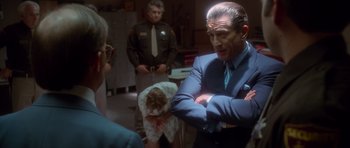 Movie still from “Casino” (1995), directed by Martin Scorsese – A man in a blue suit is standing in front of two other people; Medium shot, Over the shoulder angle