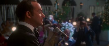 Movie still from “Casino” (1995), directed by Martin Scorsese – A man is speaking into a microphone in front of a crowd of onlookers; Close Up shot, Over the shoulder angle