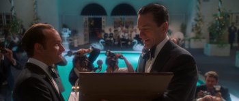 A man wearing a suit and tie standing in front of a microphone