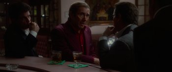 Movie still from “Casino” (1995), directed by Martin Scorsese – A man sitting at a table talking to another man; Medium shot, Over the shoulder angle