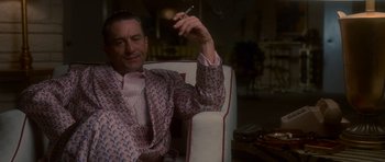 Movie still from “Casino” (1995), directed by Martin Scorsese – A man sitting in a chair holding a cigarette in his hand; Medium shot, Low angle