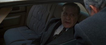 Movie still from “Casino” (1995), directed by Martin Scorsese – An older man in a suit sitting in the back seat of a car; Medium shot, High angle
