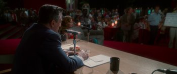 Movie still from “Casino” (1995), directed by Martin Scorsese – A man sitting in front of a microphone at a table; Wide shot, Over the shoulder angle
