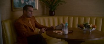 Movie still from “Casino” (1995), directed by Martin Scorsese – A man sitting at a table in front of a box of cigarettes; Medium shot, Low angle