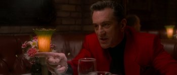 Movie still from “Casino” (1995), directed by Martin Scorsese – A man sitting at a table with a glass of wine; Close Up shot, Over the shoulder angle