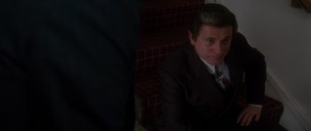 Movie still from “Casino” (1995), directed by Martin Scorsese – A man in a suit sitting on some steps; Medium shot, High angle