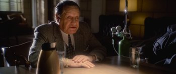 Movie still from “Casino” (1995), directed by Martin Scorsese – An older man sitting at a table with a glass of water; Close Up shot, High angle