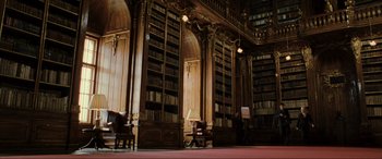 Movie still from “Casino Royale” (2006), directed by Martin Campbell – A room filled with lots of bookshelves and chairs; Wide shot, Low angle
