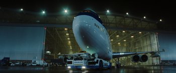 Movie still from “Casino Royale” (2006), directed by Martin Campbell – A large airplane in a hangar with people standing around it; Extreme Wide shot, Low angle