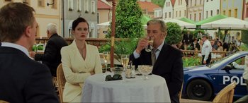Movie still from “Casino Royale” (2006), directed by Martin Campbell – A man and a woman sitting at an outdoor table drinking champagne; Medium shot, Over the shoulder angle