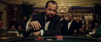 Movie still from “Casino Royale” (2006), directed by Martin Campbell – A man sitting at a poker table with a watch on his hand; Medium shot, Over the shoulder angle
