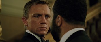 Movie still from “Casino Royale” (2006), directed by Martin Campbell – A man in a suit and tie looking at another man in a suit and tie; Close Up shot, Over the shoulder angle