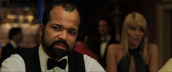 Movie still from “Casino Royale” (2006), directed by Martin Campbell – A man with a beard wearing a black bow tie; Close Up shot, Over the shoulder angle