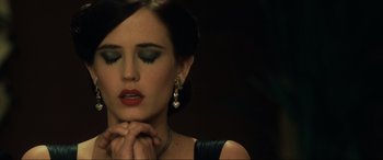 Movie still from “Casino Royale” (2006), directed by Martin Campbell – A beautiful woman wearing a black dress and gold jewelry; Close Up shot, High angle
