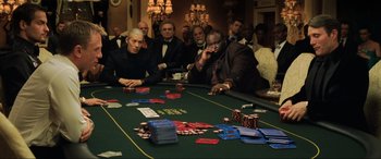 Movie still from “Casino Royale” (2006), directed by Martin Campbell – A group of people sitting around a table with cards; Medium shot, High angle