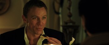 Movie still from “Casino Royale” (2006), directed by Martin Campbell – A person eating a piece of pizza; Close Up shot, Over the shoulder angle