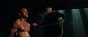 Movie still from “Casino Royale” (2006), directed by Martin Campbell – A man in a black suit is holding a rope; Medium shot, Low angle