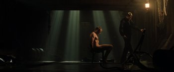 Movie still from “Casino Royale” (2006), directed by Martin Campbell – A naked man sitting in a chair in front of some lights; Wide shot, Low angle
